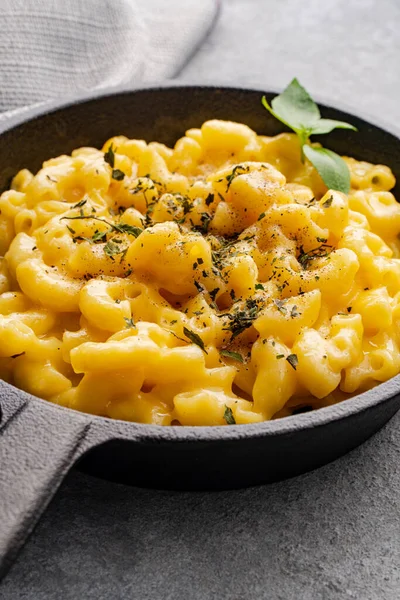 Gri taş arka planda lezzetli bir tavada peynirli makarna