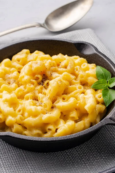 Gri taş arka planda lezzetli bir tavada peynirli makarna
