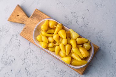 Sarı tombul acı biber. Taş masa arkasında turşu.