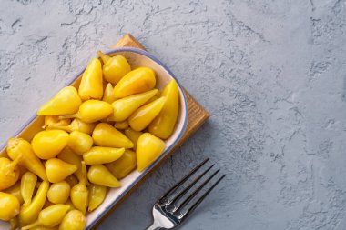 Sarı tombul acı biber. Taş masa arkasında turşu.