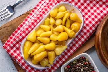 Sarı tombul acı biber. Taş masa arkasında turşu.