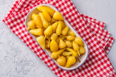 Sarı tombul acı biber. Taş masa arkasında turşu.