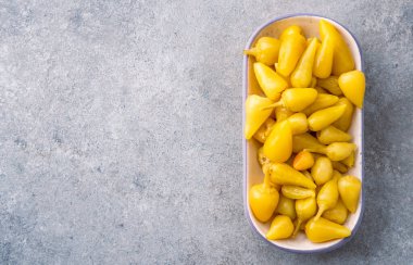 Sarı tombul acı biber. Taş masa arkasında turşu.