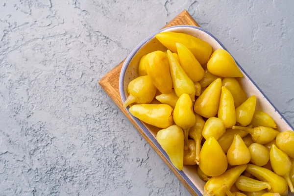 Sarı tombul acı biber. Taş masa arkasında turşu.