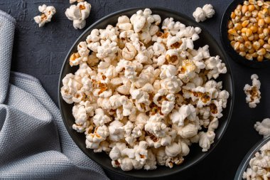 Siyah taş masa arkasında kasede nefis patlamış mısır..