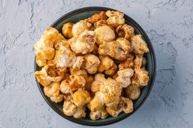 Taş masa arkasındaki kasede nefis patlamış mısır..