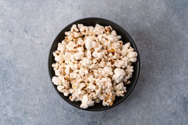 Taş masa arkasındaki kasede nefis patlamış mısır..