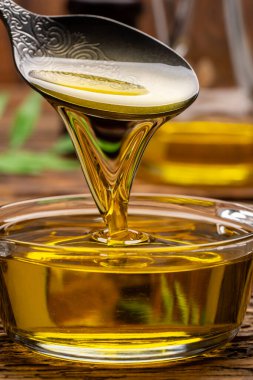 Organik zeytin yağı, kaşıktan cam kaseye dökülüyor ahşap masada.