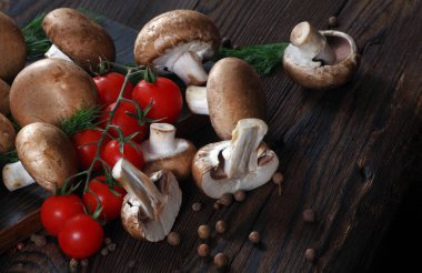 Tahta bir masada taze mantar şampiyonları, domatesler ve baharatlar. en üstteki görünüm