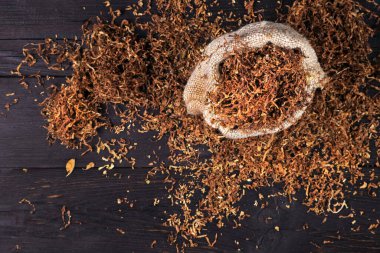 Ahşap bir masada kuru tütün yaprağı ve sigara. Kapat.