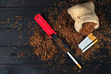 Kuru tütün yaprağı, sigara ve sigara makinesi ahşap masada. El yapımı sigara.
