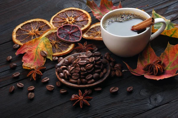 autumn coffee. coffee in a white cup, dried citrus fruits and spices on a wooden table. dry colorful maple leaves and a cup of coffee. autumn mood