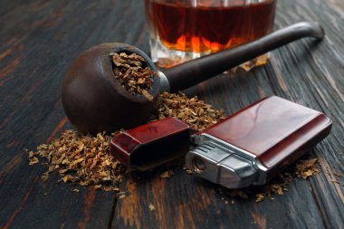 Tütünlü pipo ve ahşap bir masada bir bardak viski.