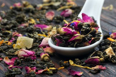 Kaşık içinde gül yaprakları olan kuru yeşil çay yaprakları. 