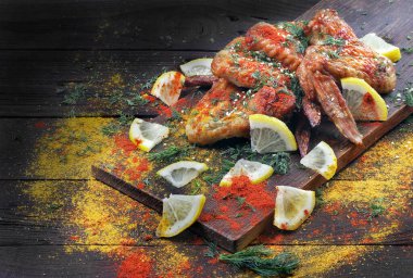 Ahşap bir masada ızgara tavuk kanadı ve baharat.