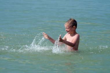 Çocuk denizde banyo yapıyor. su oyunları