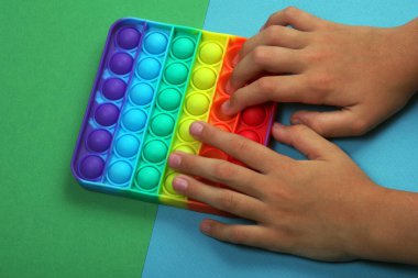 Popüler silikon renkli anti-stres oyuncağı yeşil ve mavi arka plandaki çocuklar için. en üstteki görünüm