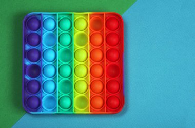 Popüler silikon renkli anti-stres oyuncağı yeşil ve mavi arka plandaki çocuklar için. en üstteki görünüm