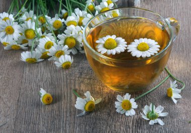 Tahta bir masada cam bir fincanda bitkisel papatya çayı. Kapat. şifalı bitkiler