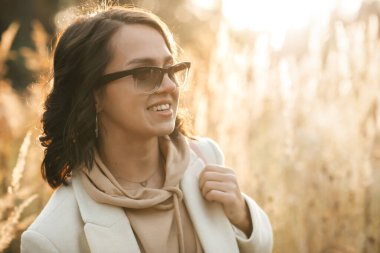 Gün batımında tarlada güneş gözlüklü esmer kızın portresini kapat.