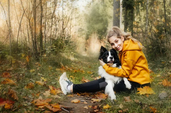 秋林里带着黑白相间的边境牧羊犬的姑娘 — 图库照片