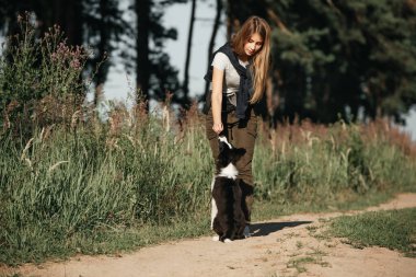 Siyah-beyaz sınırda çoban köpeği eğiten bir kız.