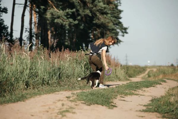 Siyah-beyaz sınırda çoban köpeği eğiten bir kız.