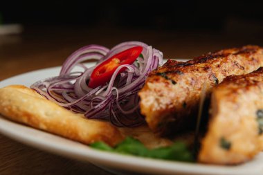 Beyaz tabakta pide ekmekli Lula kebabı