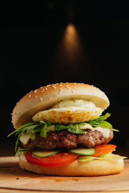 Haşlanmış yumurtalı sığır burger yakın plan. Hamburger - çörek, ızgara et burger, roka salatası, domates ve kızarmış yumurta..
