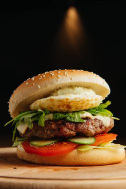 Haşlanmış yumurtalı sığır burger yakın plan. Hamburger - çörek, ızgara et burger, roka salatası, domates ve kızarmış yumurta..