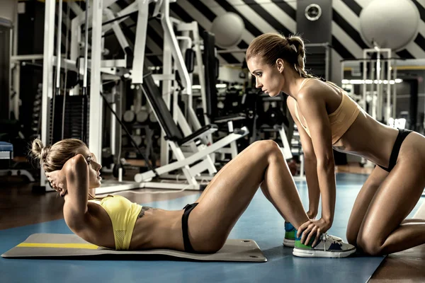 Zwei junge Fitnessfrauen führen Übung durch — Stockfoto