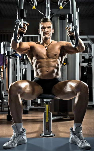 Bodybuilder on gym apparatus — Stock Photo, Image