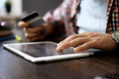 Tablet bilgisayarı ve kredi kartı olan adam.
