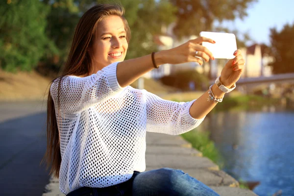 Bela jovem selfie no parque com um smartphone — Fotografia de Stock