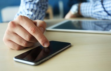 Modern cihazlar, dijital tablet bilgisayar ve cep telefonuyla çalışan genç işadamı