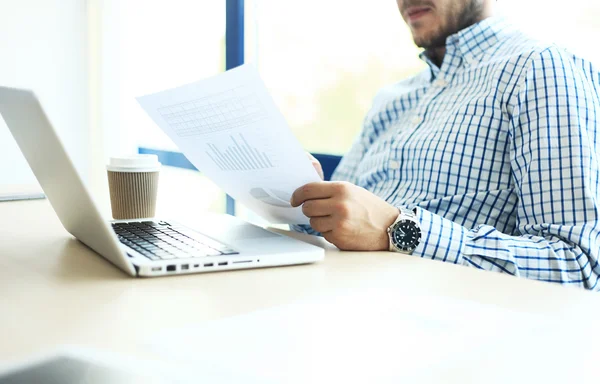 Деловой человек, работающий в офисе с ноутбуком и документами на столе — стоковое фото