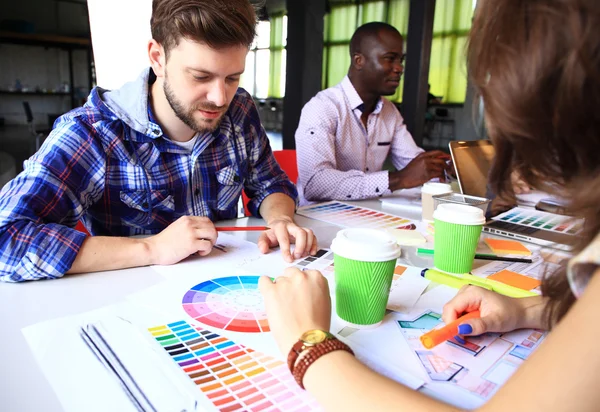 Gente creativa lugar de trabajo. Vista de cerca de las manos de la joven diseñadora que trabaja con la paleta de colores en el escritorio de la oficina. Modelo atractivo eligiendo muestras de color para el proyecto de diseño . — Foto de Stock