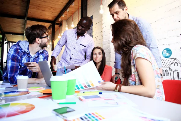 Making great decisions. Young beautiful woman gesturing and discussing something with smile while her coworkers listening to her sitting at office table — Stock Photo, Image