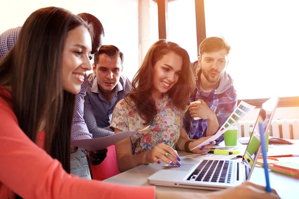 Het nemen van goede beslissingen. Jonge mooie vrouw gebaren en bespreken van iets met glimlach terwijl haar collega's luisteren naar haar zittend op kantoor tafel — Stockfoto