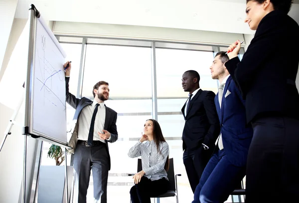 Fröhlicher Geschäftsmann diskutiert mit den Mitgliedern seines Teams über ein neues Geschäftsprojekt — Stockfoto