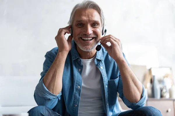 Head shot man sit on sofa in living room makes video call looks at camera, conversation by distant videocall