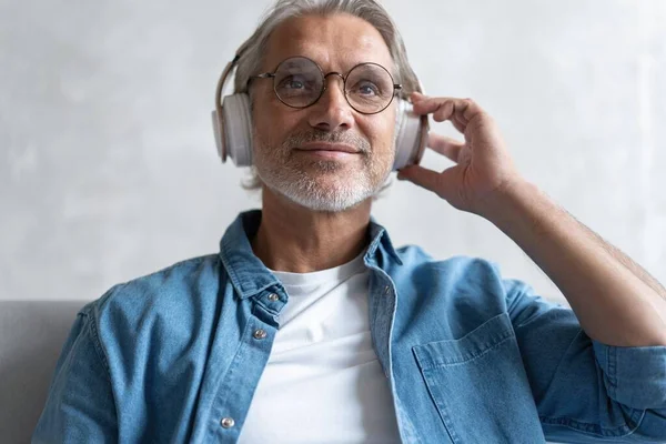 Hombre en casa en el sofá escuchando una música con un smartphone. — Foto de Stock