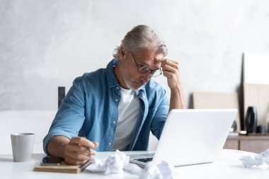 Stresli serbest çalışanın başı ağrıyor ve işini nasıl bitireceğini düşünüyor, evinde oturuyor ve acı çekiyor.