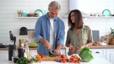 Mutlu çift evde birlikte yemek pişiriyor. Evli çift ev mutfağında flört ediyor.