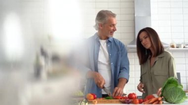 Mutlu çift evde birlikte yemek pişiriyor. Evli çift ev mutfağında flört ediyor.