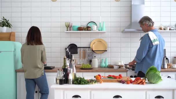 Mutlu çift evde birlikte yemek pişiriyor. Evli çift ev mutfağında flört ediyor. — Stok video