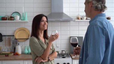 Bardak tutan mutlu çift mutfakta konuşuyor, kırmızı şarap içiyor.