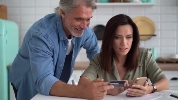 Szczęśliwa para zakup on-line za pomocą karty kredytowej i smartfona, płacenie pożyczki — Wideo stockowe