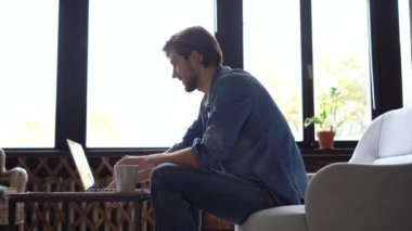 Gülümseyen profesyonel iş adamı evde dizüstü bilgisayarda çalışıyor.