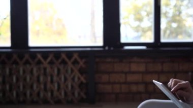 Kulaklıklı çekici bir genç adam evdeki tabletten video izliyor.